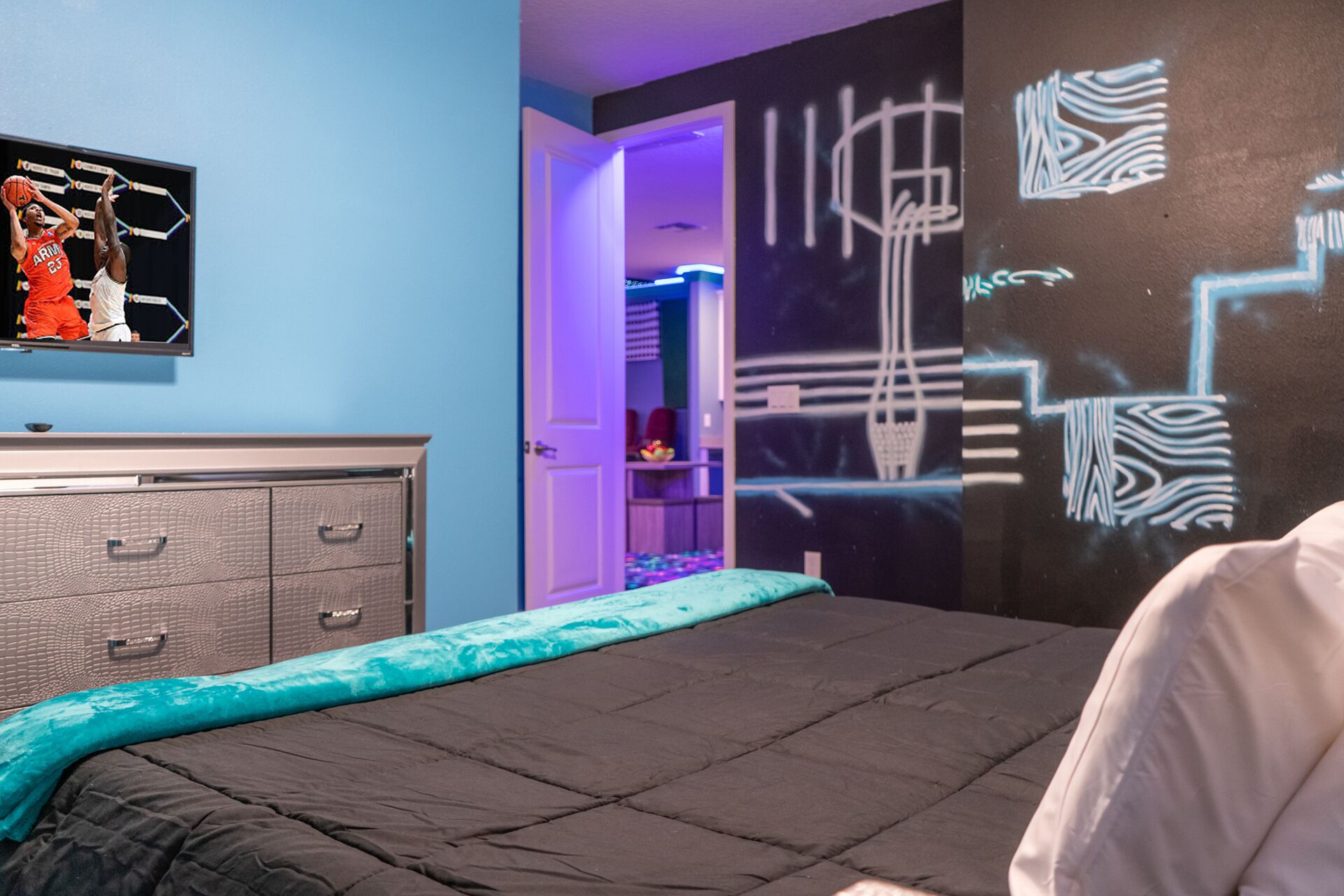 Ein modernes Schlafzimmer mit Bett, Kommode und einer Wand mit abstrakter Kunst.