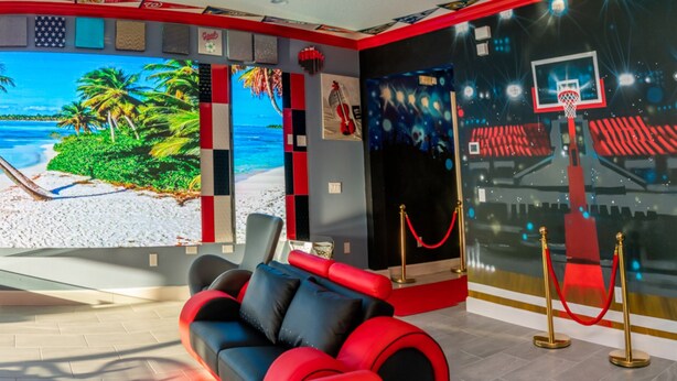 A modern lounge with a large screen displaying a beach scene, comfortable seating, and a glass coffee table.