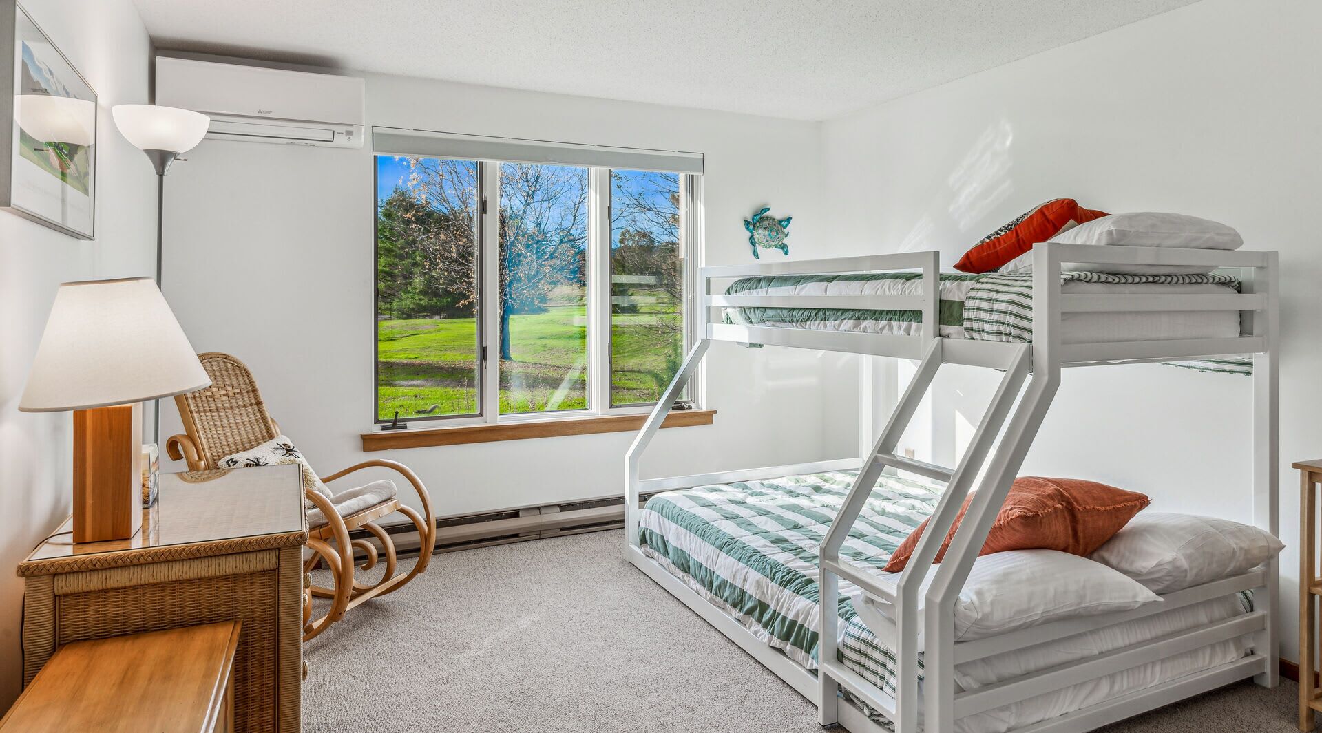 Een slaapkamer met een stapelbed en uitzicht op een groen landschap door een groot raam.