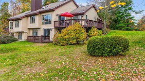 A two-story house with a balcony, a red umbrella, and a well-maintained lawn.