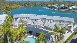 A modern resort with multiple buildings, a swimming pool, and a view of the sea.