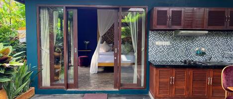 Une chambre avec une porte-fenêtre coulissante, un lit à baldaquin et une vue sur un jardin.