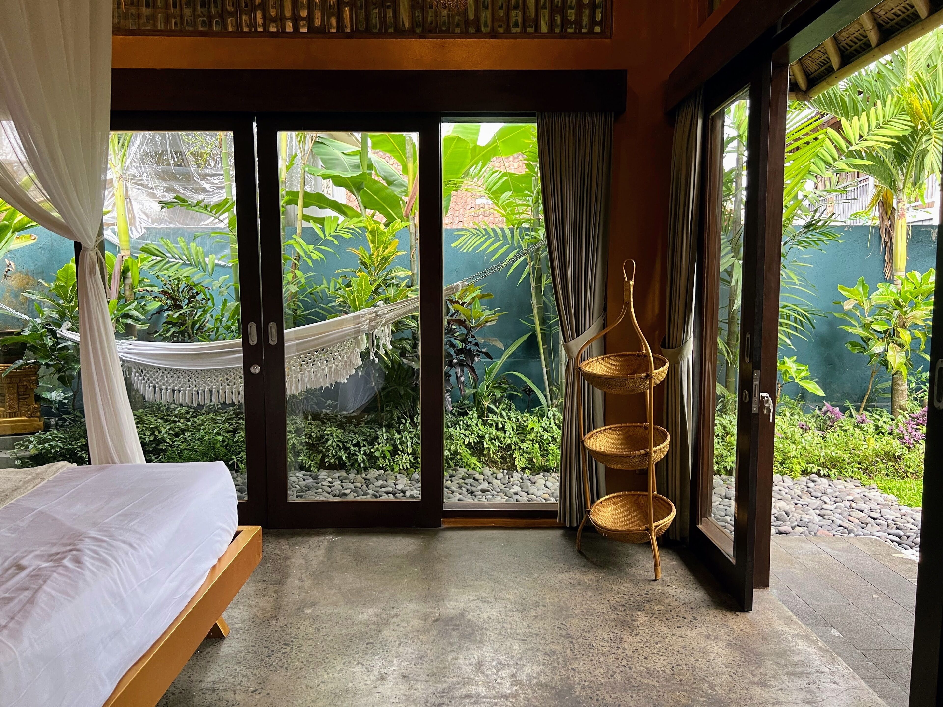 A bedroom with a bed, a hammock, and a wicker basket.