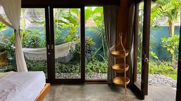 A bedroom with a bed, a hammock, and a wicker basket.