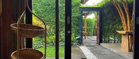 A traditional Japanese garden with a stone pathway, bamboo, and a wooden structure.