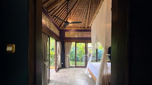 A room with a bed, a ceiling fan, and a view of greenery through large windows. - Joyously Raw Villas (Ubud)