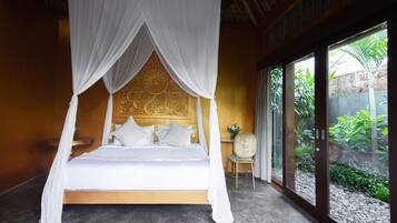 A bed with a canopy, a chair, and a view of greenery through large windows.