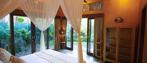 A bedroom with a bed, curtains, and a view of a garden.