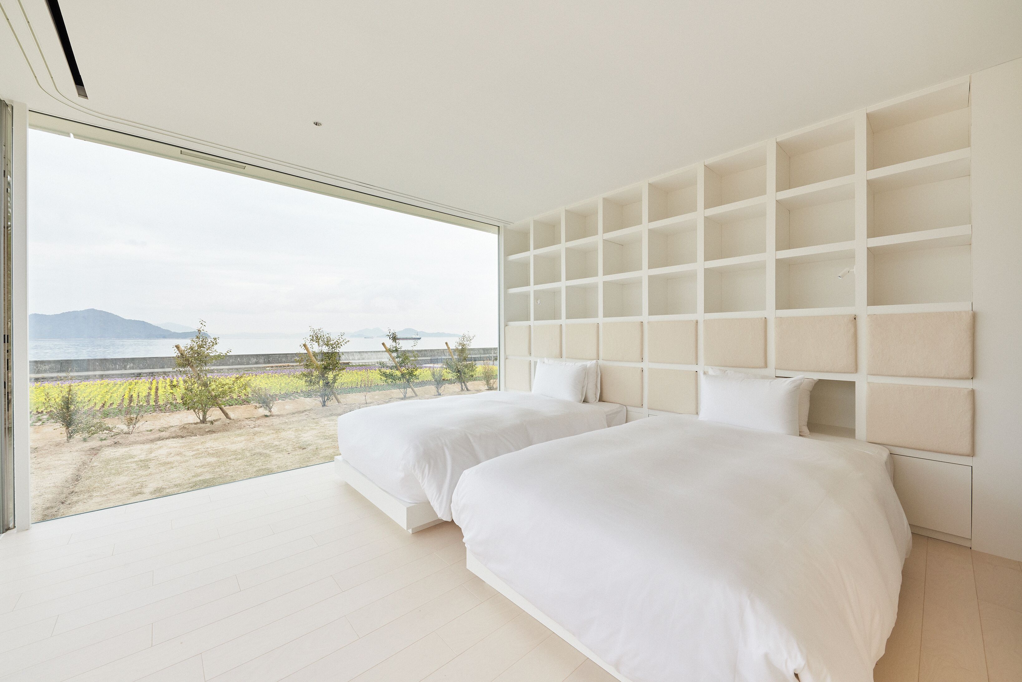 Une chambre avec deux lits, une grande fenêtre et une vue sur un paysage.