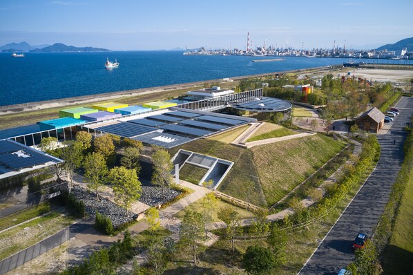 Zona industrial con paneles solares, un estacionamiento y una masa de agua con barcos.