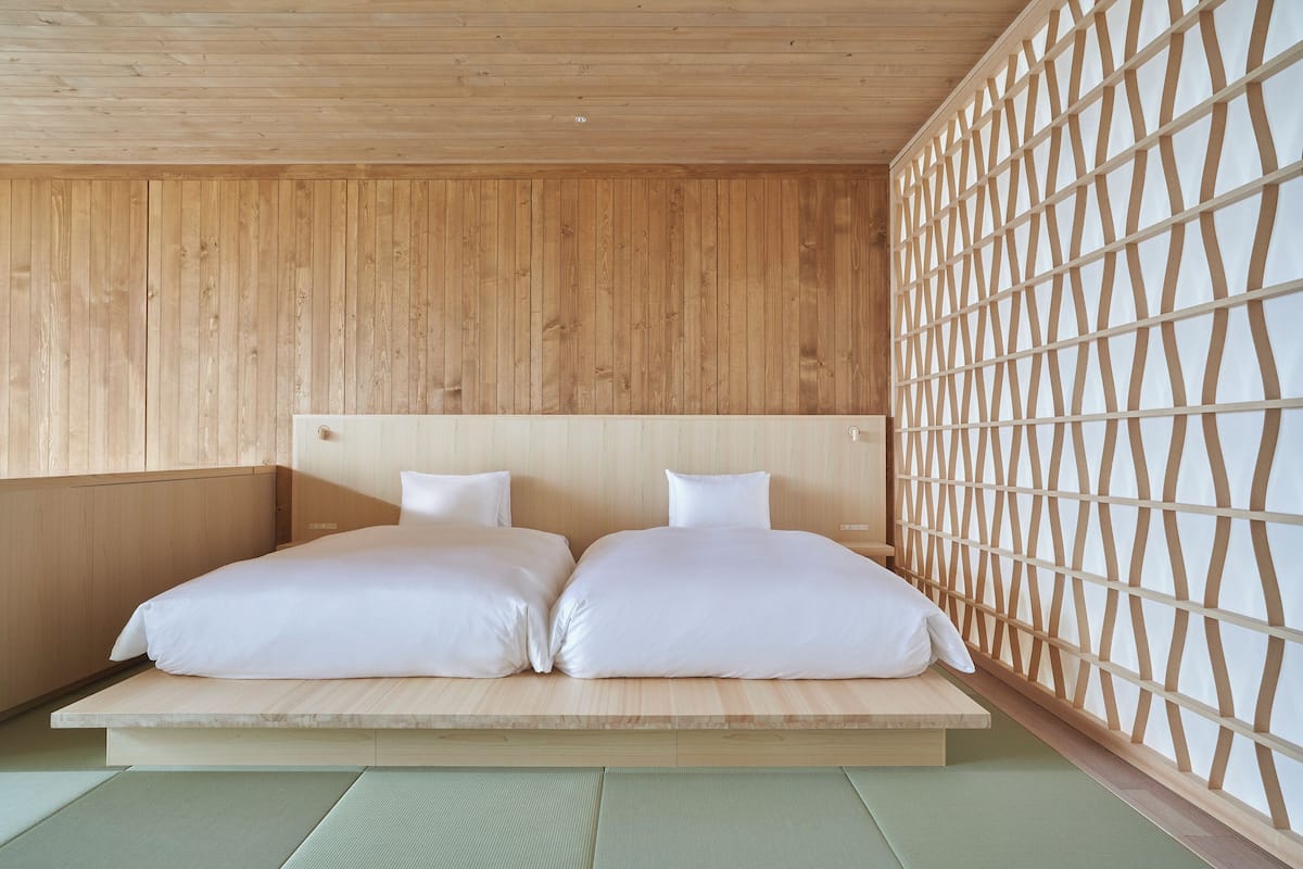 A room with a low platform bed, wooden walls, and a lattice partition.