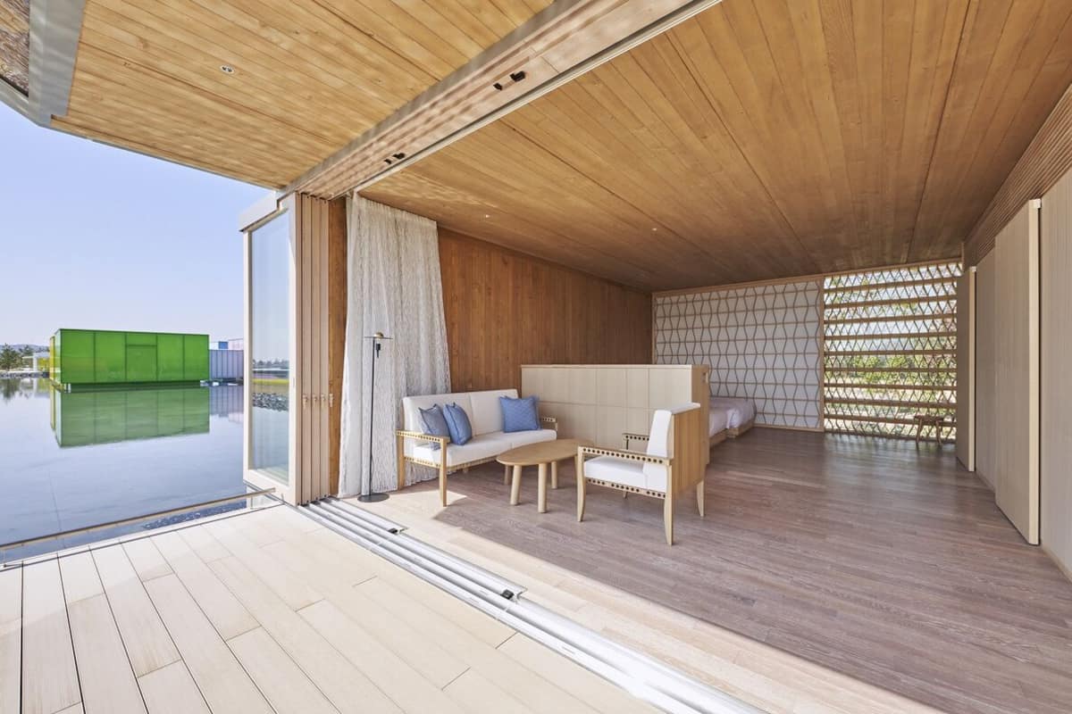A modern interior with a wooden ceiling, a sofa, a chair, and a glass door leading to a pool.