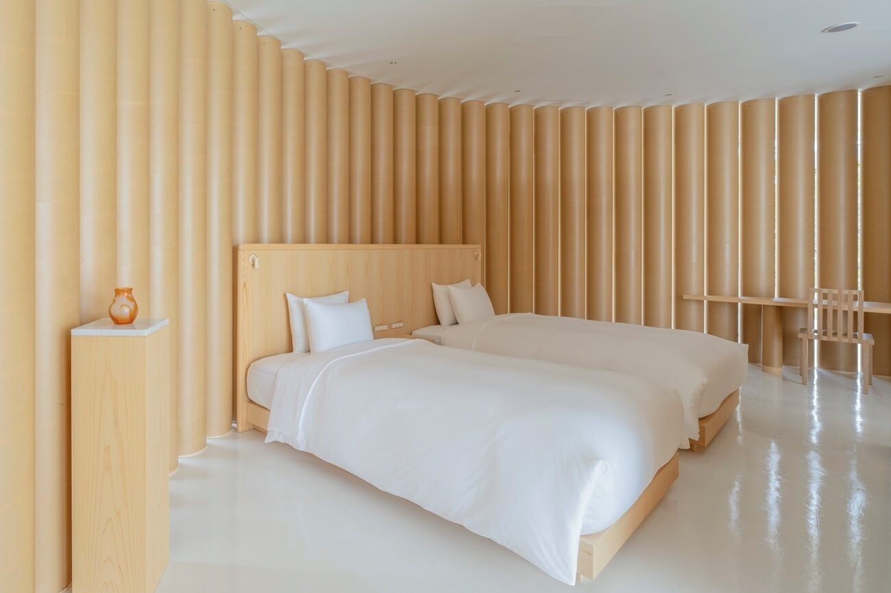 Una habitación de hotel moderna con una cama grande, una mesita de noche y una silla.