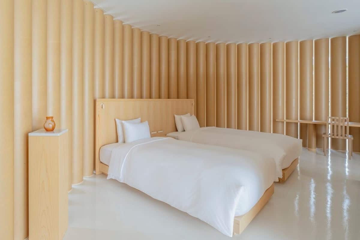 A modern hotel room with a large bed, a bedside table, and a chair.
