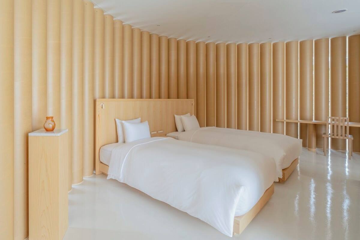 Una habitación de hotel moderna con una cama grande, una mesita de noche y una silla.