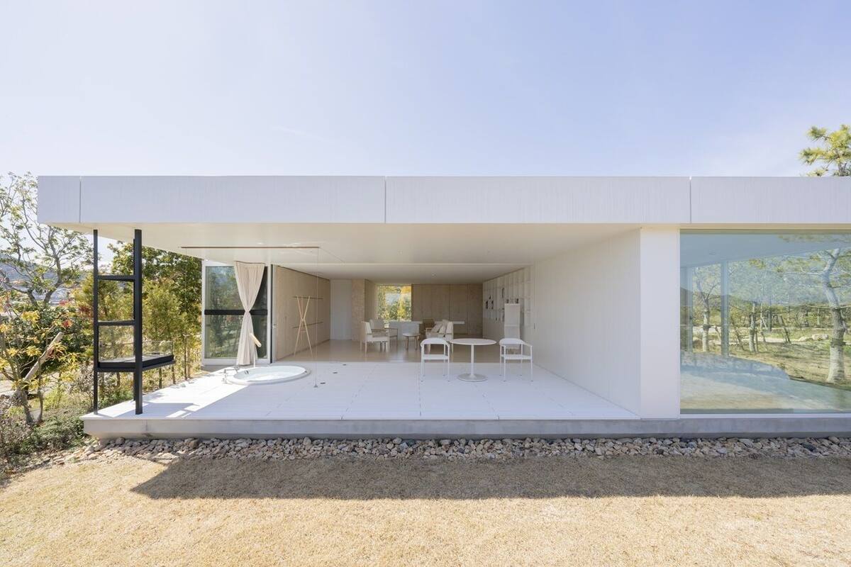 A modern house with a patio, outdoor seating, and large windows.
