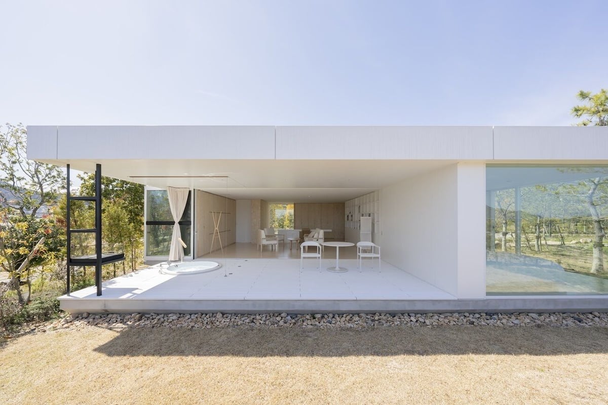 A modern house with a patio, outdoor seating, and large windows.