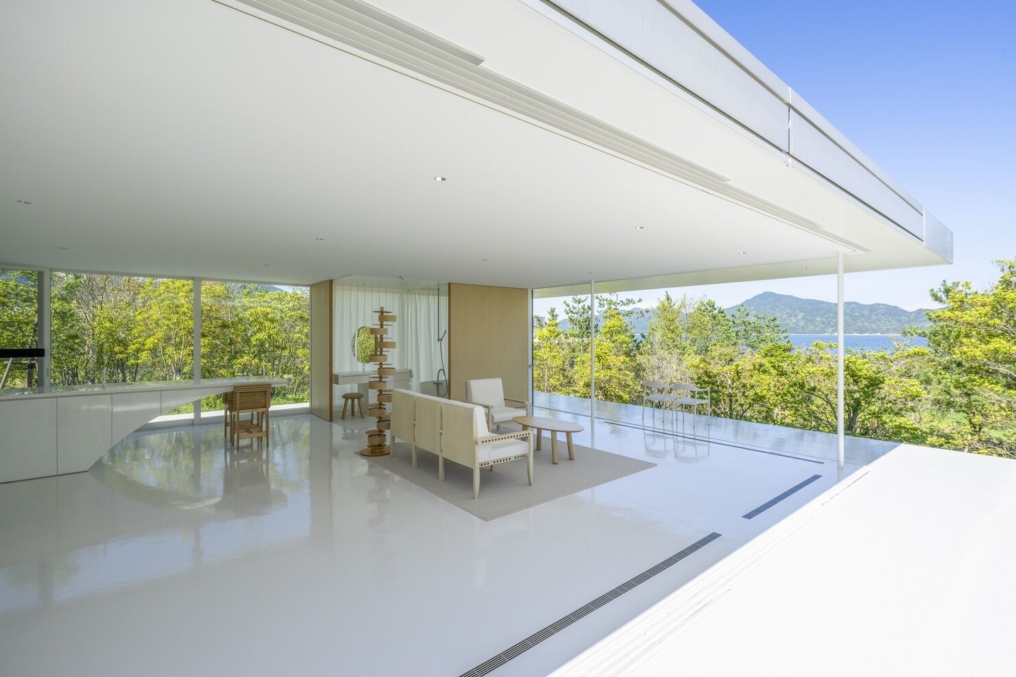 Un intérieur moderne avec une grande baie vitrée, un canapé, une table à manger et un élément décoratif original.
