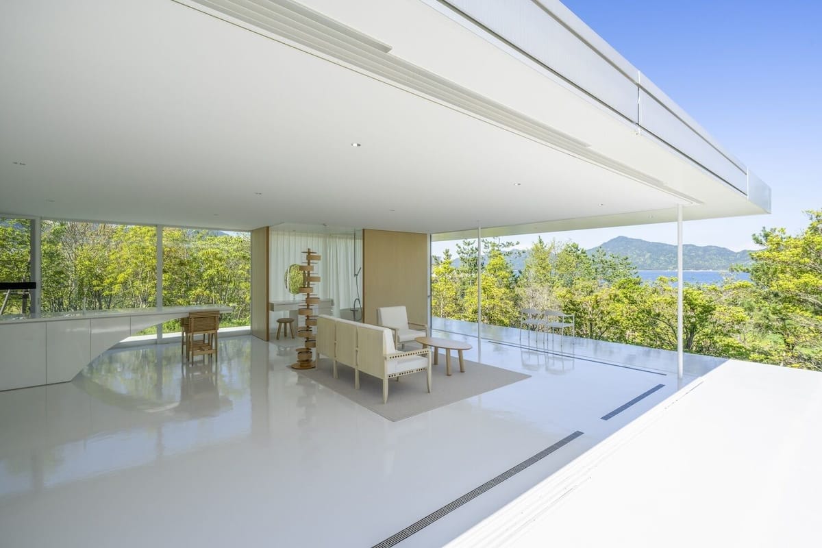 A modern interior with a large glass window, a sofa, a dining table, and a unique decorative piece.