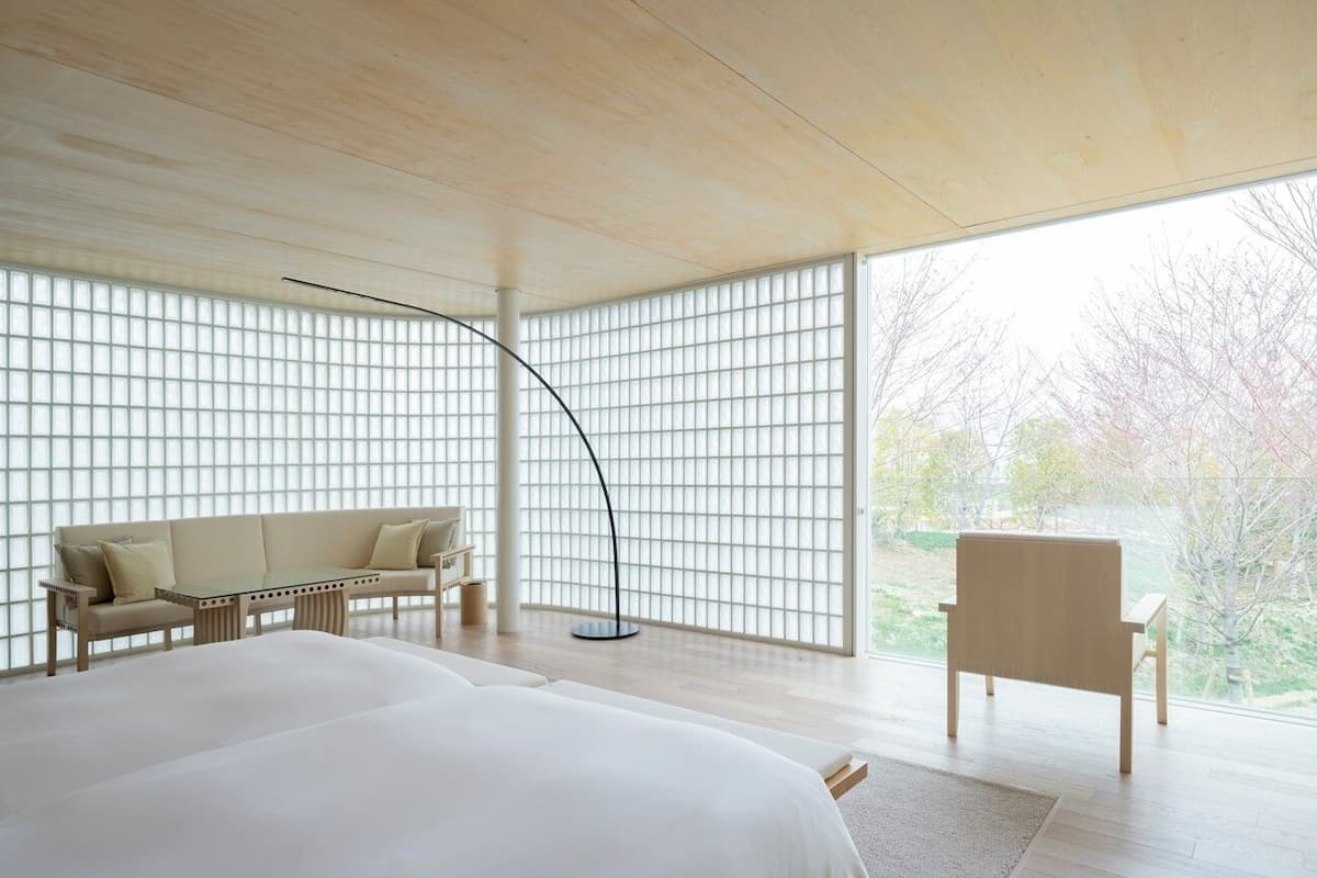 A modern bedroom with a large bed, a sofa, a table, and a chair.