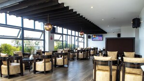 A spacious indoor area with multiple seating arrangements, large windows, and a television screen. - Swiss-Belinn Nairobi (Nairobi)