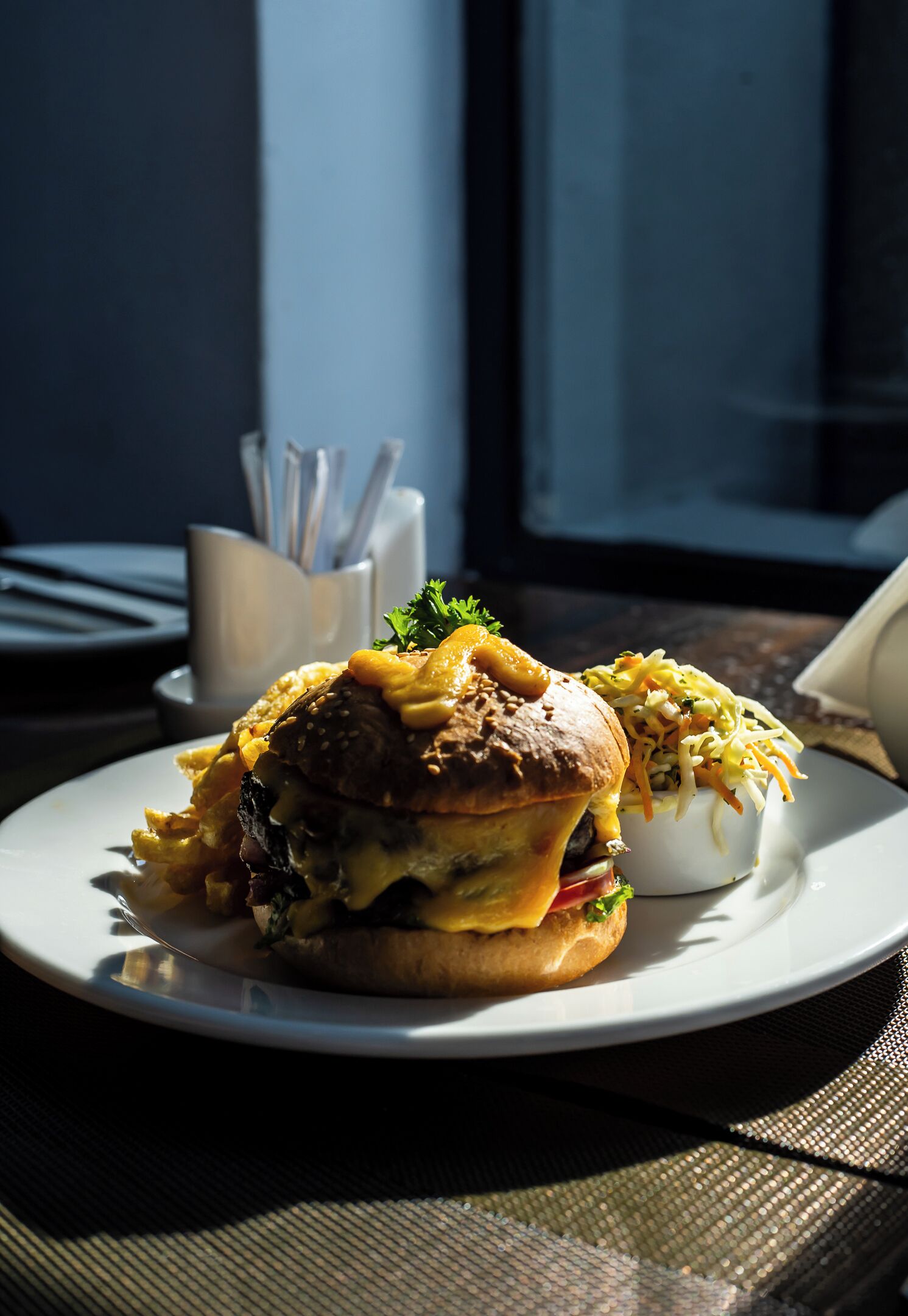 A plate with a burger and a side salad on a table.