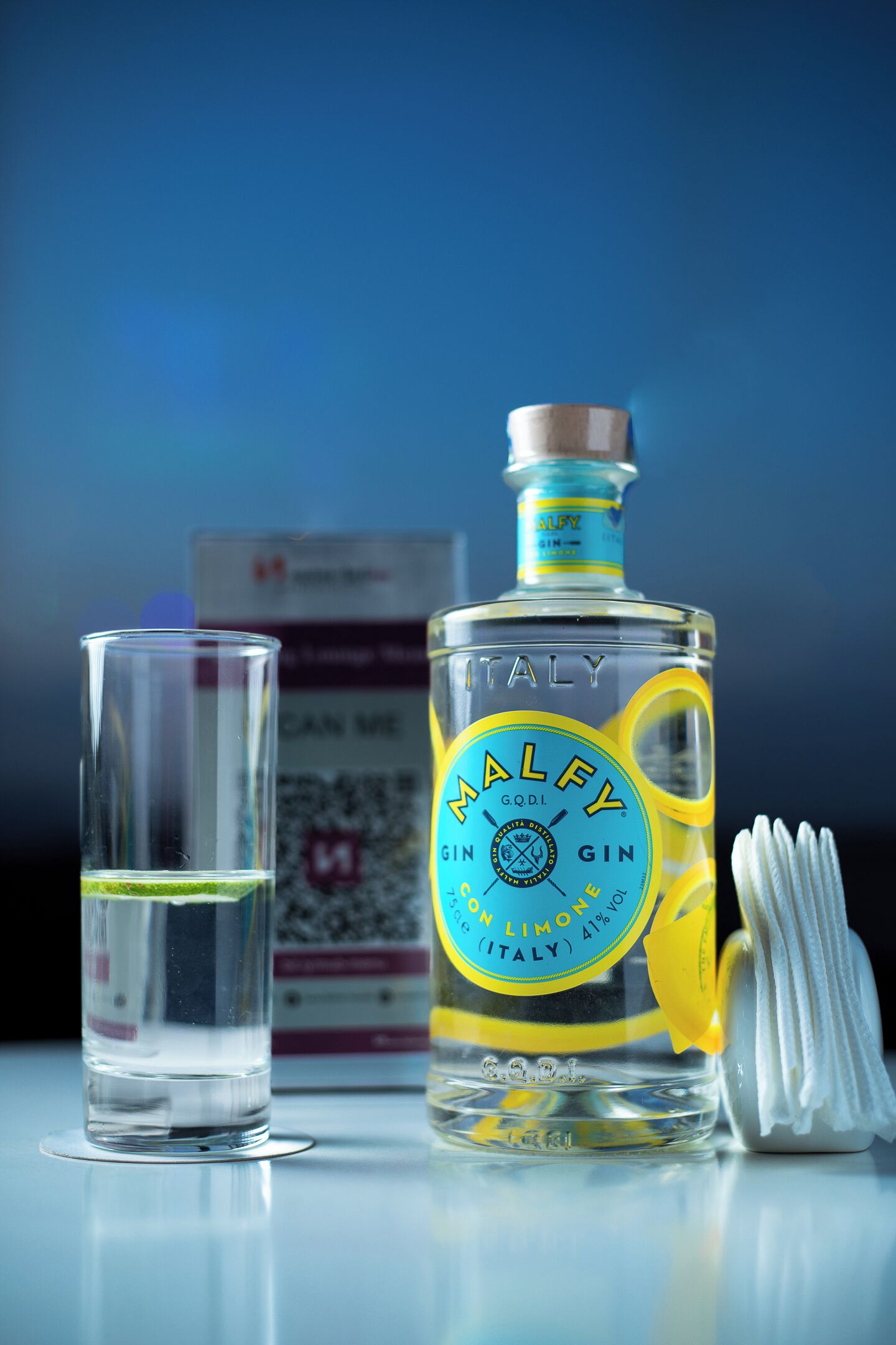 A bottle of Malfy Gin and a shot glass on a reflective surface.