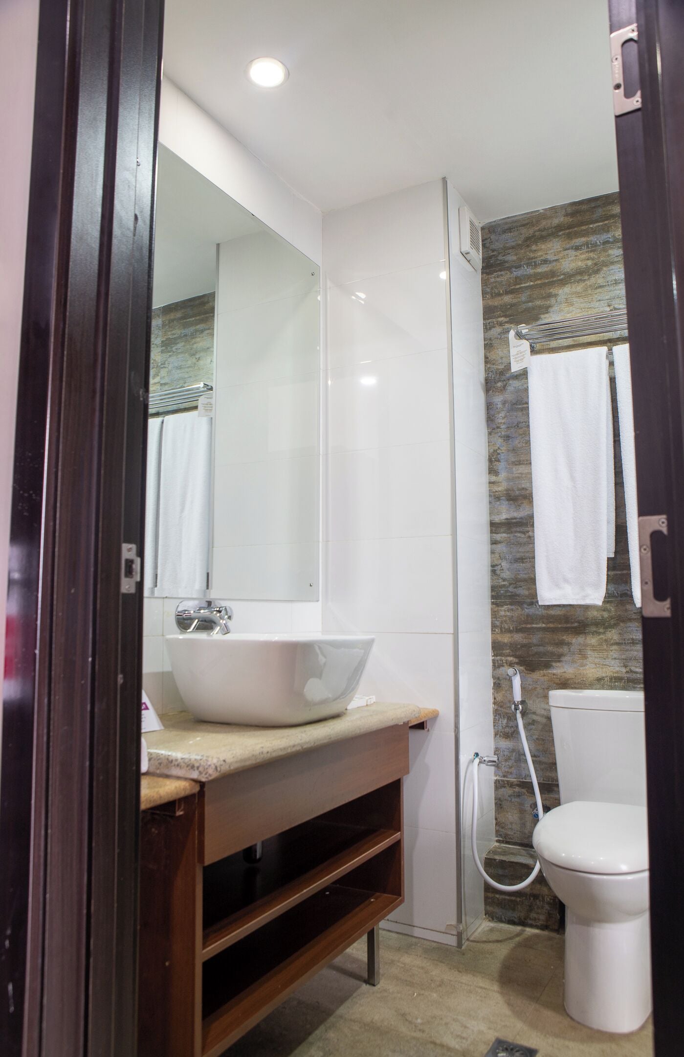 Une salle de bain moderne avec un grand miroir, un lavabo blanc, une douche et des toilettes.