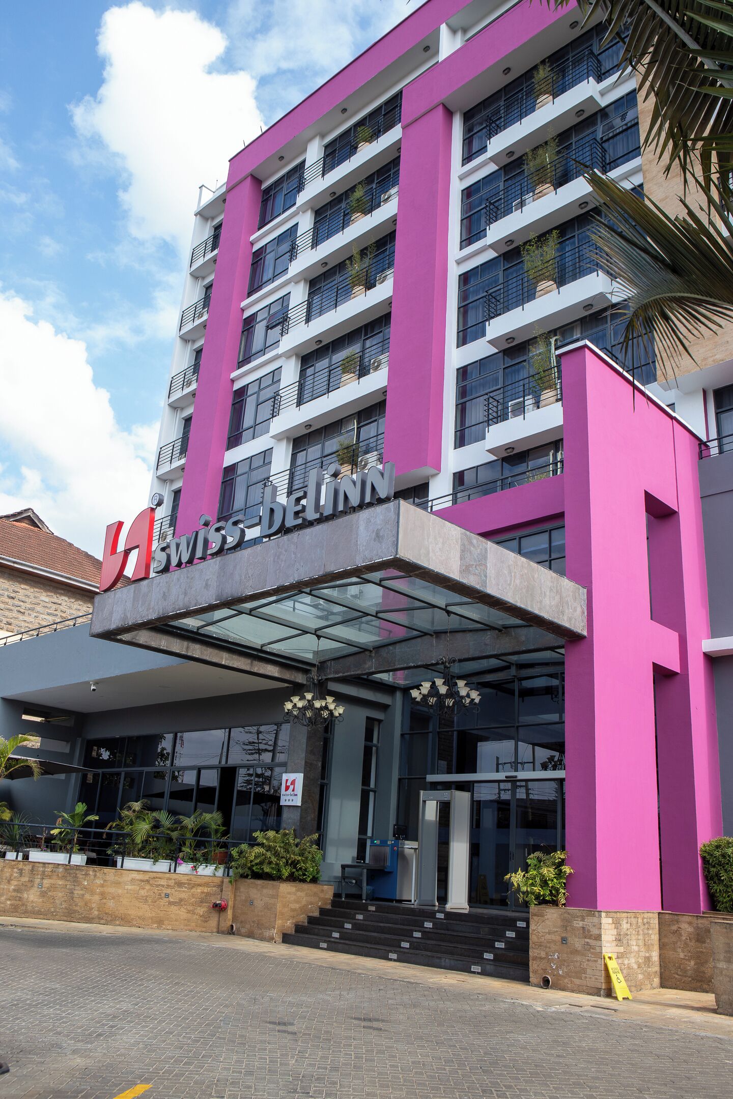 A modern building with a prominent pink facade and the sign "SWISS-BELIN".