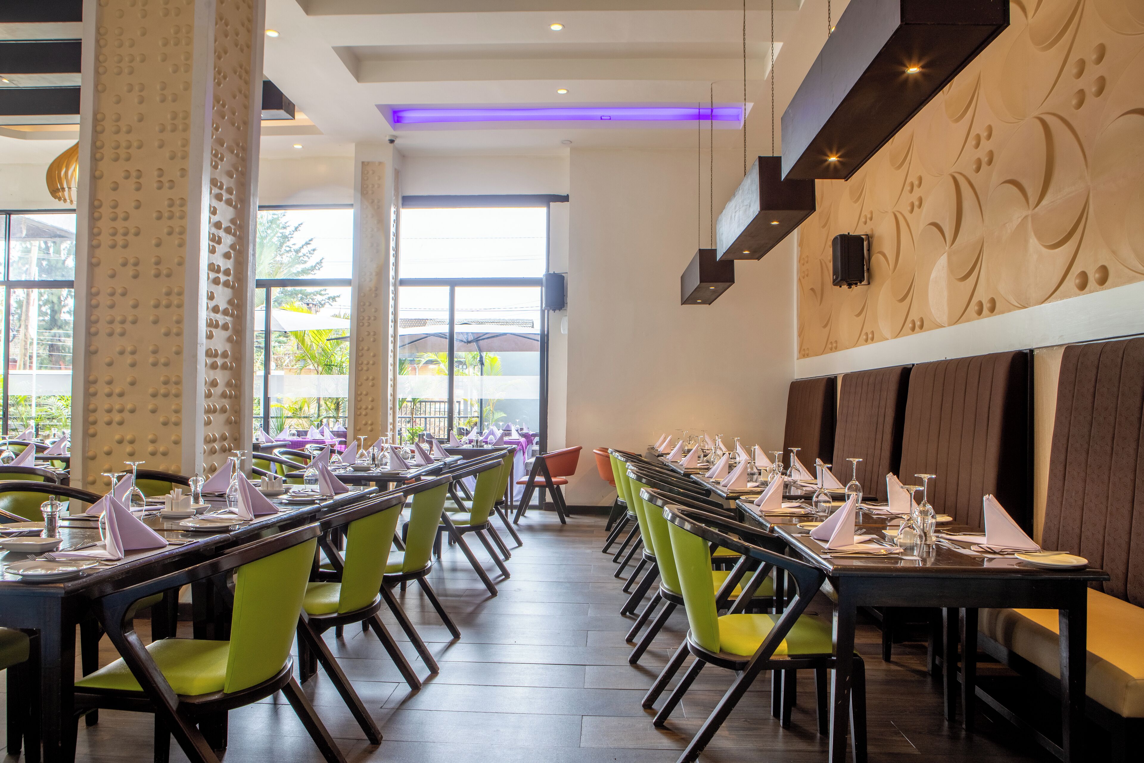 A restaurant with long tables, green chairs, and a modern interior design.