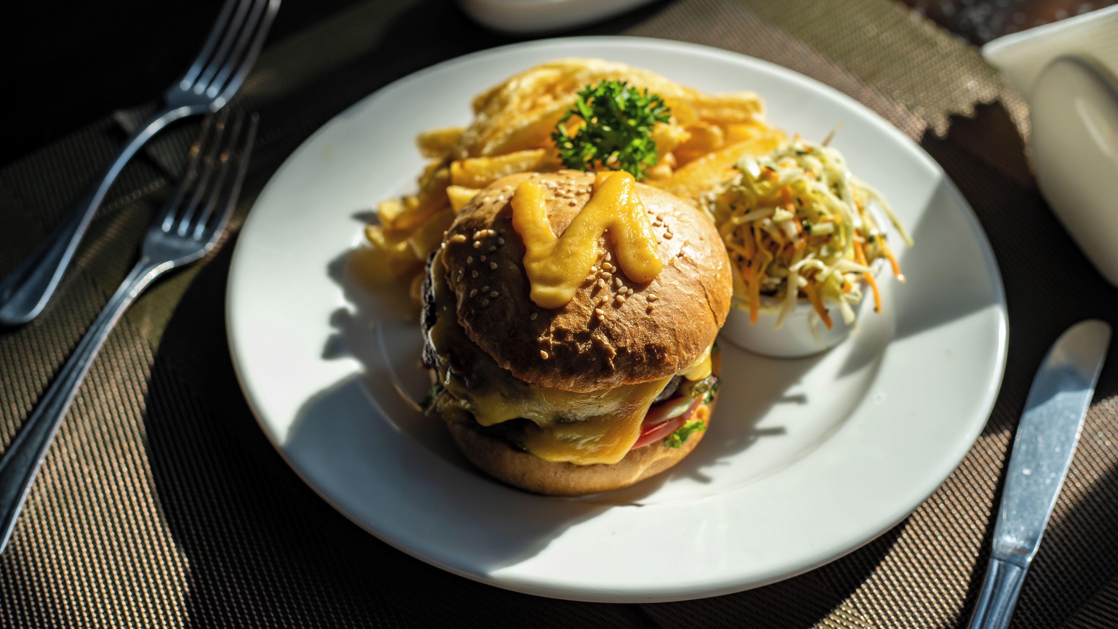 A plate with a sandwich, coleslaw, and a small bowl of sauce.