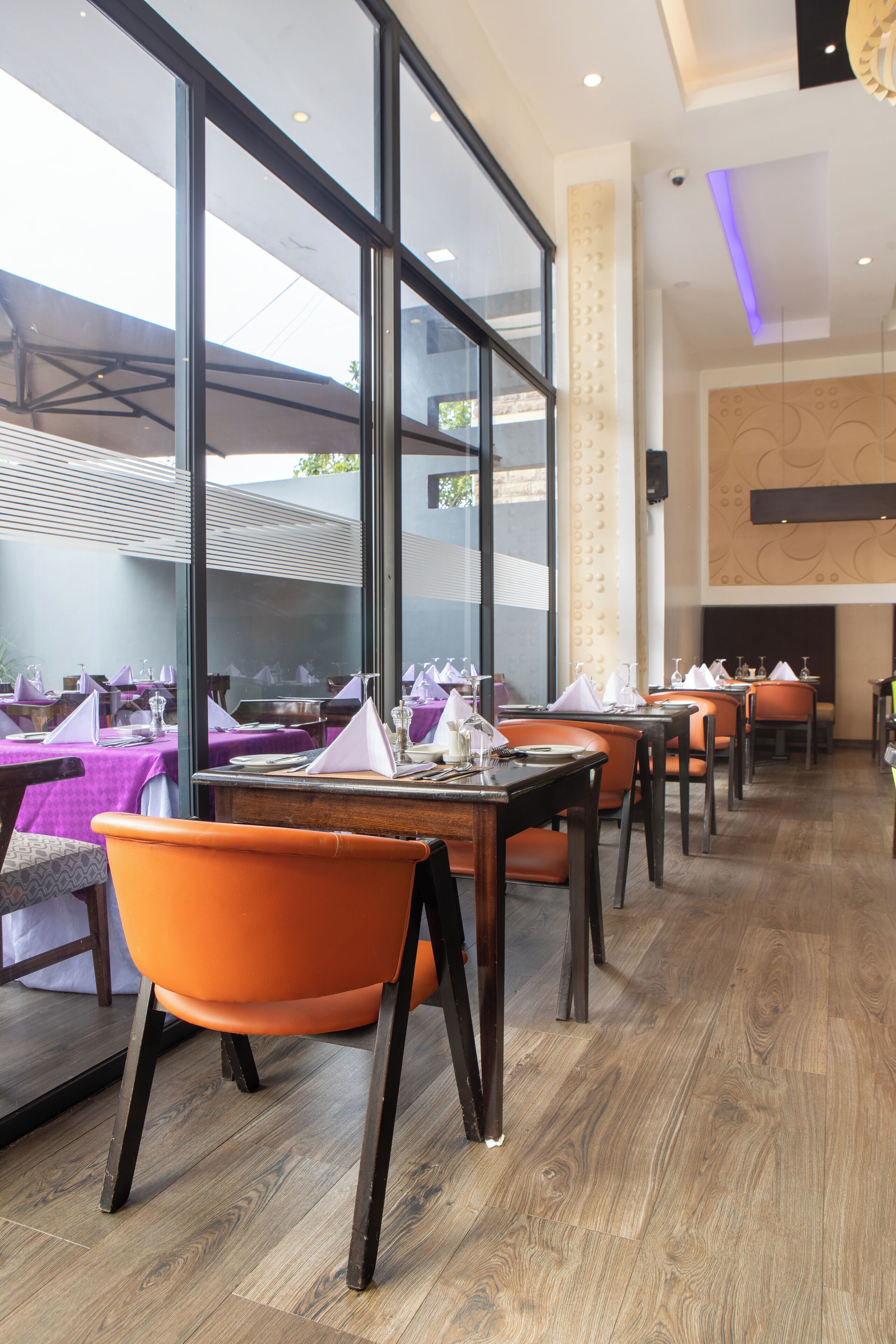 A restaurant with tables set for dining, large windows, and a modern interior design.