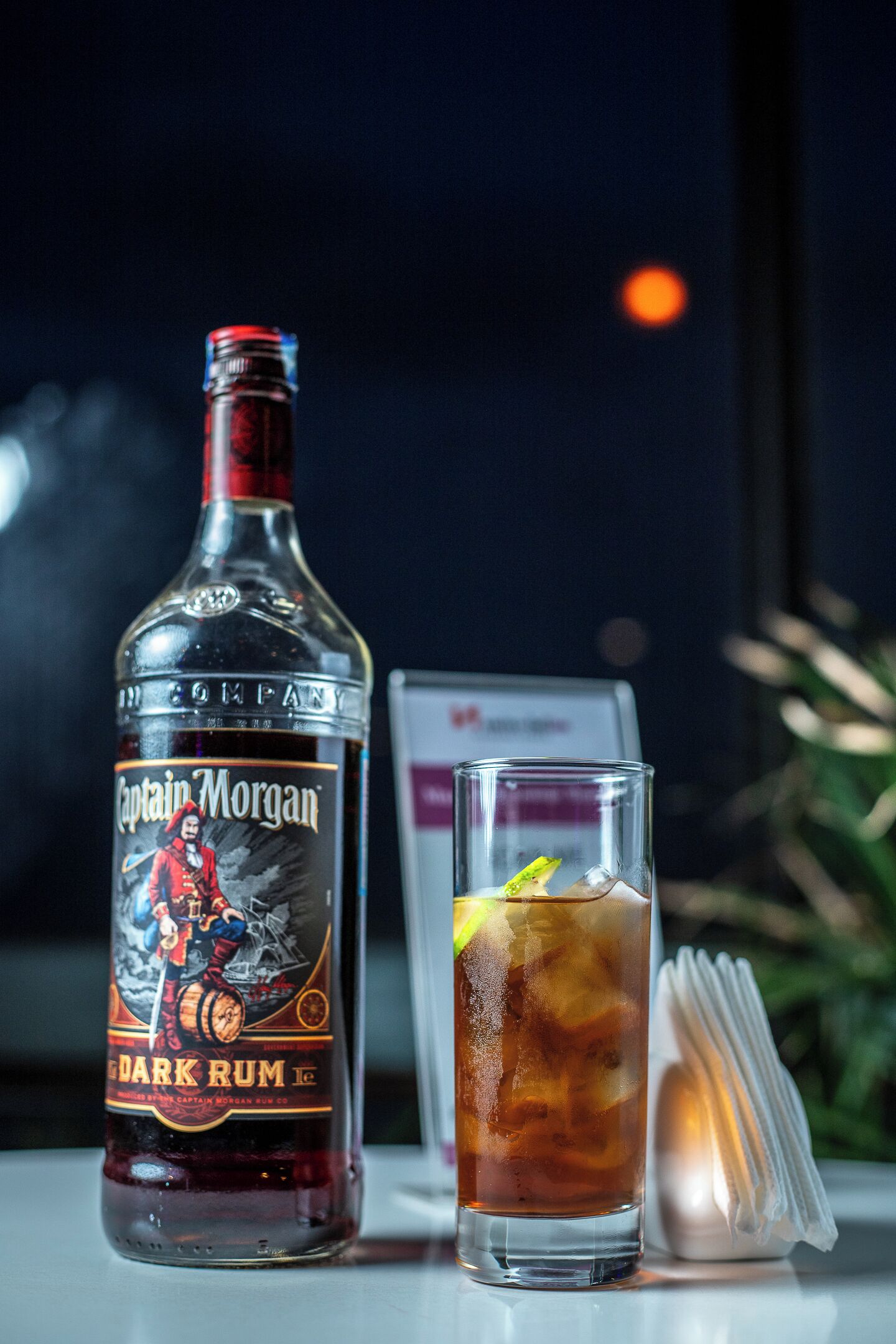Une bouteille de rhum Captain Morgan Dark et un verre avec une tranche de citron.