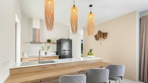 Een moderne keuken met een houten aanrechtblad, roestvrijstalen apparatuur en een eethoek met grijze bekleden stoelen.