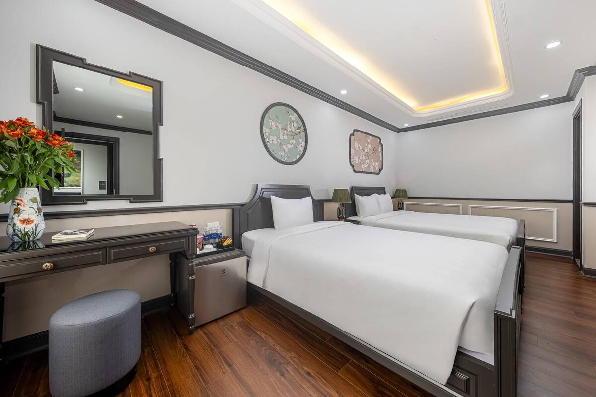 Una habitación de hotel con una cama grande, un escritorio, una silla, una mesita y un espejo.
