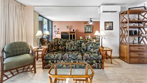Un salon comprenant un canapé, des fauteuils, une table basse et une bibliothèque en bois.