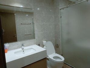 A modern bathroom with a white sink, toilet, and a glass shower enclosure.