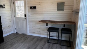 Une pièce aux murs en bois, avec une porte, une fenêtre et un banc.