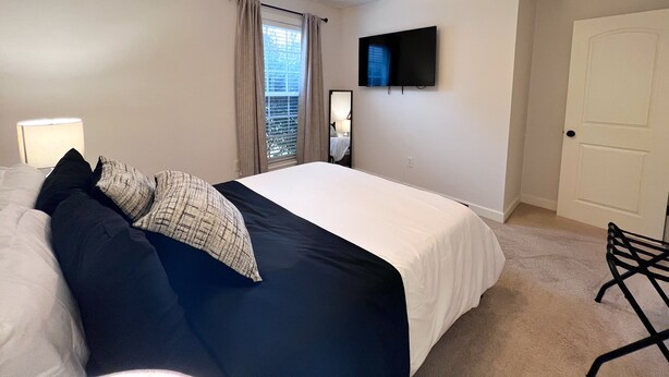 Une chambre à coucher avec un lit, une lampe de chevet, un téléviseur, une porte et une chaise.