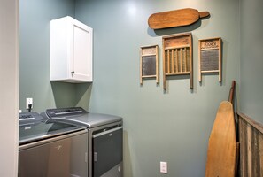 Un lavadero con lavadora y secadora Whirlpool, una tabla de remo de madera y lavadoras antiguas de funcionamiento manual en la pared.