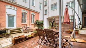 A courtyard with a wooden deck, outdoor seating, and a bicycle.