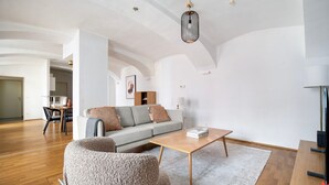 A modern living room with a grey sofa, wooden coffee table, and a hanging light fixture.