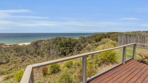 Una terraza de madera con vista al océano y a la playa.