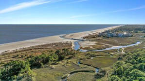 Un paysage côtier comprenant une plage, une rivière et une zone résidentielle avec des bâtiments.