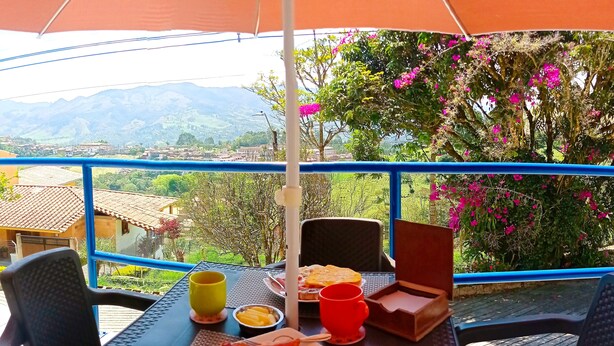 A dining table with breakfast items and a view of mountains and greenery. - JUHALU (Jericó)