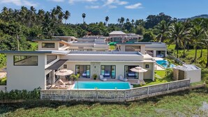 A modern multi-story house with a swimming pool, surrounded by lush greenery and palm trees. - Sereniwood 2 - 3 Bedroom Pool Villa (Koh Samui)