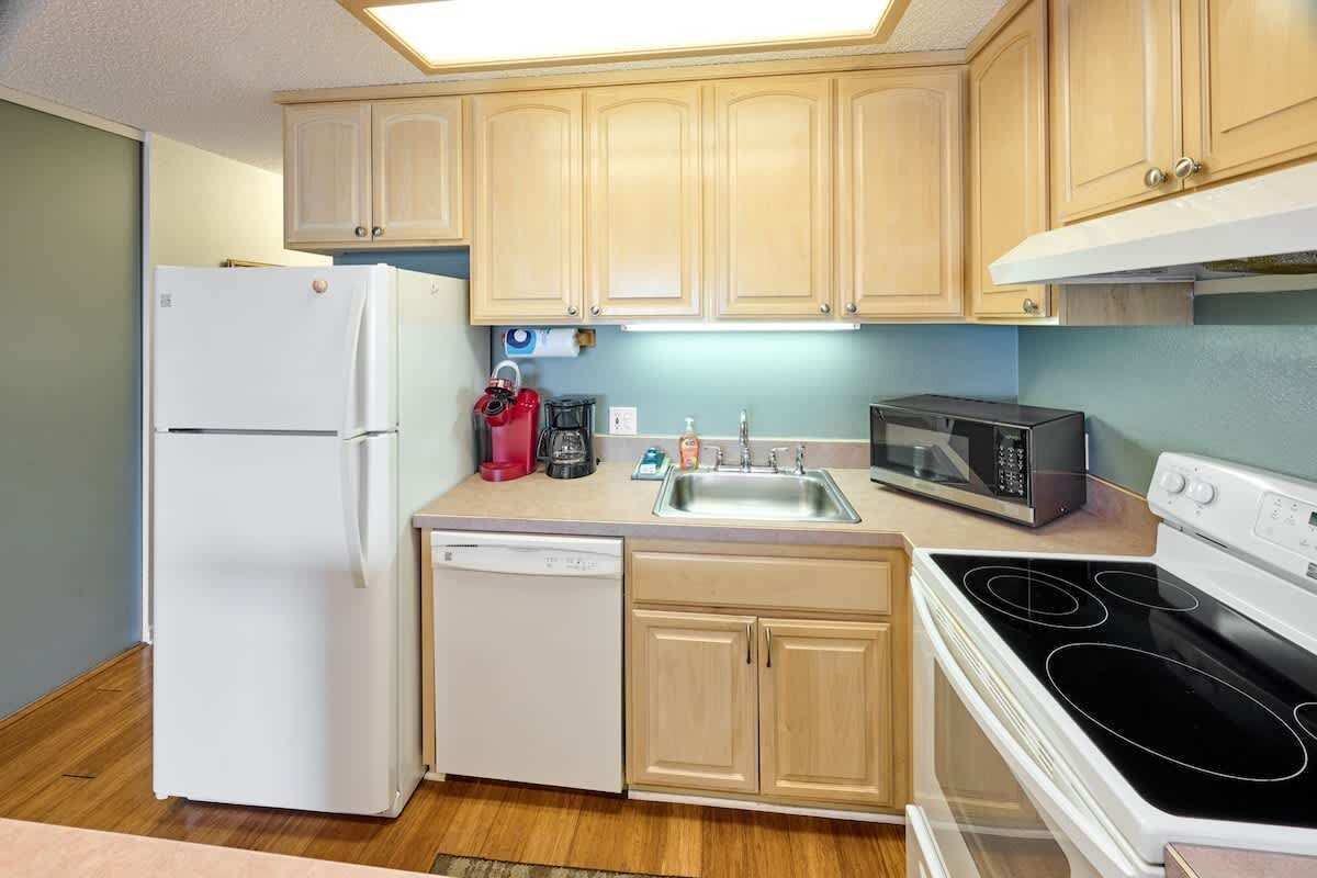 Una cocina compacta equipada con refrigerador, lavavajillas, microondas y estufa.