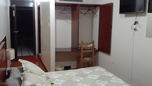 A bedroom with a bed, a chair, a TV, and a wardrobe. - HOTEL CENTRAL (Latacunga)