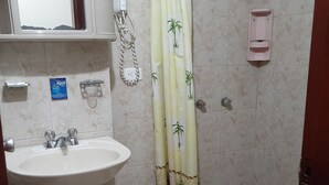 A bathroom with a white sink, a shower with a palm tree patterned curtain, and a hand dryer. - HOTEL CENTRAL (Latacunga)