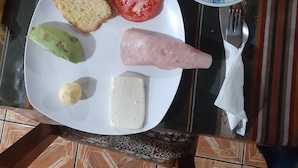 A breakfast plate with bread, tomato, cheese, and ham. - HOTEL CENTRAL (Latacunga)